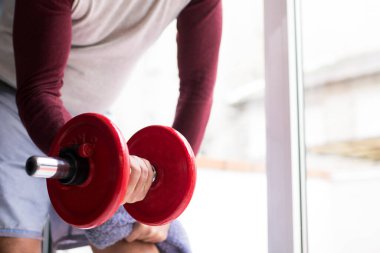 Adam spor salonunda dambıl yapıyor.