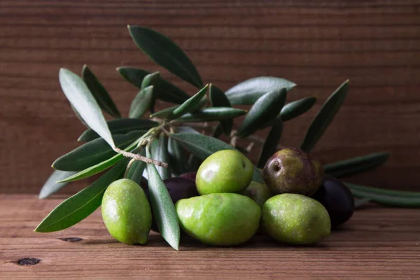 natural olives with leaves on wooden background