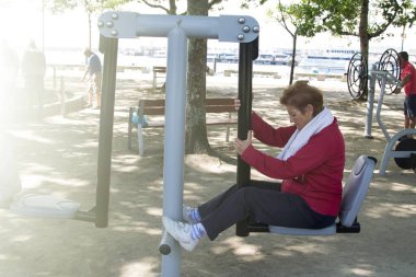 Egzersiz yapan ve dışarıda jimnastik yapan mutlu bir son sınıf kadını.