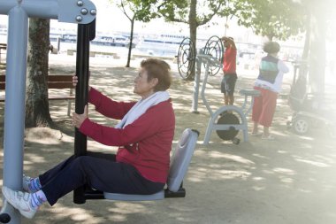 Egzersiz yapan ve dışarıda jimnastik yapan mutlu bir son sınıf kadını.