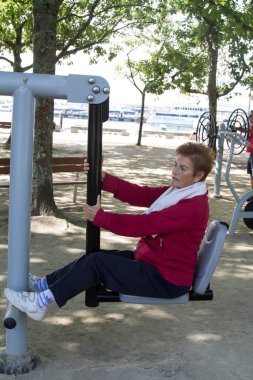 Egzersiz yapan ve dışarıda jimnastik yapan mutlu bir son sınıf kadını.