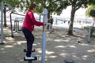 Egzersiz yapan ve dışarıda jimnastik yapan mutlu bir son sınıf kadını.