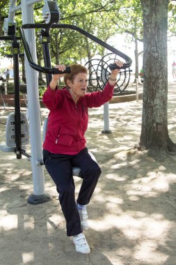 Egzersiz yapan ve dışarıda jimnastik yapan mutlu bir son sınıf kadını.