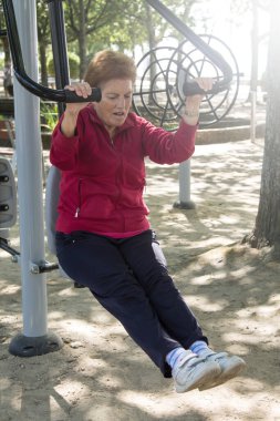 Egzersiz yapan ve dışarıda jimnastik yapan mutlu bir son sınıf kadını.