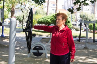 Egzersiz yapan ve dışarıda jimnastik yapan mutlu bir son sınıf kadını.