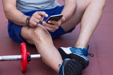 Spor salonunda cep telefonunu kullanan bir adam.