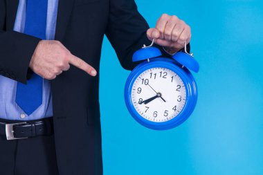İşadamı, saati parmağıyla işaret ediyor.