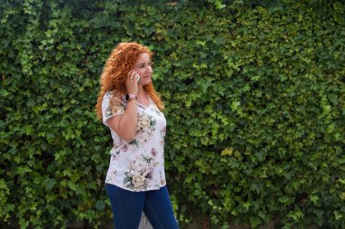 Yeşil geçmişi olan bir kadın cep telefonuyla konuşuyor.