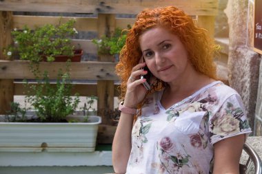 Kadın cep telefonuyla oturuyor.