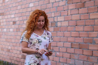 Tuğla duvarlı cep telefonu kullanan kadın