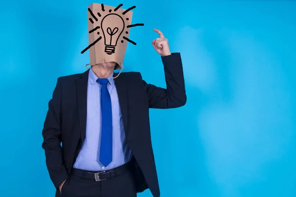 businessman with cardboard bag on his head with drawing of light bulb, concept of idea and success