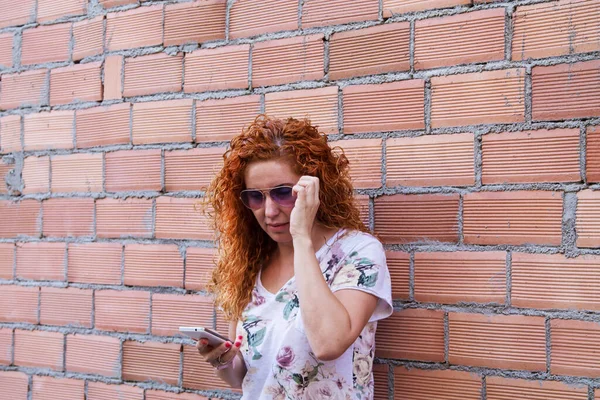 woman using mobile phone with brick wall background