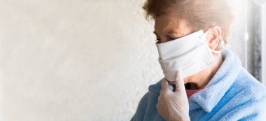 Tek kullanımlık tıbbi maskeli yaşlı bir kadının portresi. Coronavirüs salgını sırasında kamusal alanlarda güvenlik.