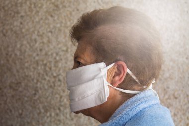 Huzurevinde tıbbi maske takan yaşlı bir kadının portresi. Koronavirüs salgını sırasında kamusal alanlarda güvenlik.