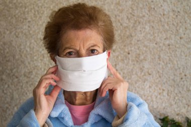Tıbbi maske takan yaşlı bir kadının portresi. Koronavirüs salgını sırasında genel güvenlik.