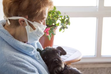 Tek kullanımlık tıbbi maskesi ve köpeği olan yaşlı bir kadının portresi. Coronavirüs salgını sırasında kamusal alanlarda güvenlik.