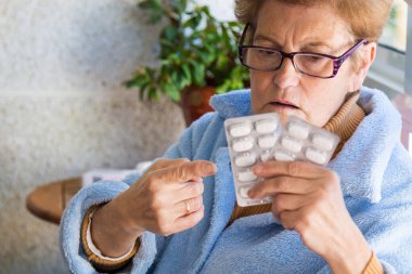 Enfeksiyonlar, virüsler ve hastalıklar için önleyici hapları elinde tutan yaşlı kadın