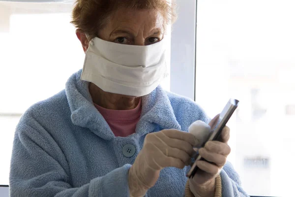 Starší Žena Lékařskou Maskou Dezinfikující Mobilní Telefon Bavlnou Alkoholem Aby — Stock fotografie