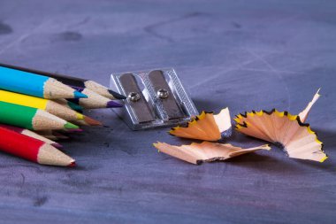 Tahtada renkli kalemler ve kalemtıraşlar, okula dönüş konsepti.