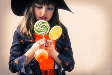 Cadı gibi giyinmiş, lolipop ve balkabaklı bir kız. Mutlu Cadılar Bayramı