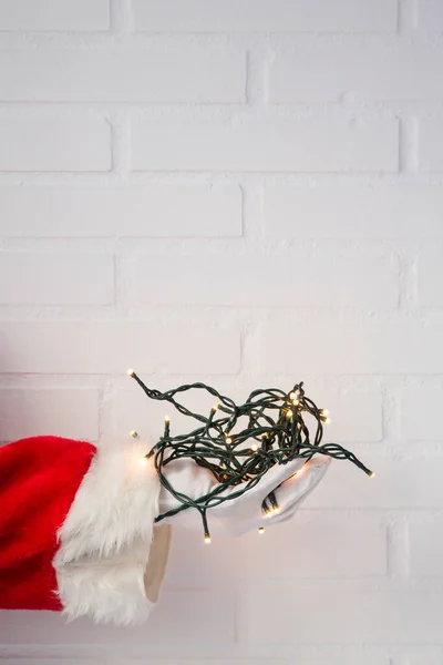 サンタクロースの手は背景にクリスマスライトを保持 — ストック写真