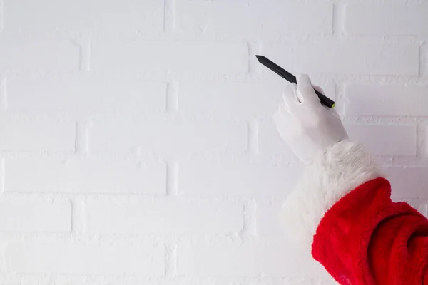 圣诞老人用钢笔在白砖墙上写字 — 图库照片