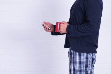 Adam cep telefonu kullanıyor ve kahve içiyor.