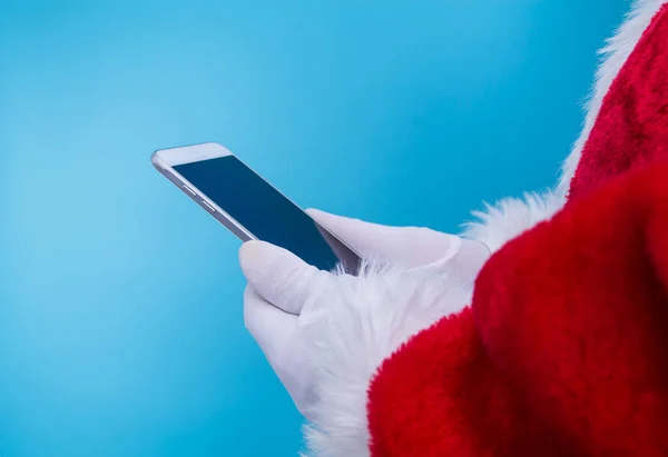圣诞老人拿着手机 蓝色背景的圣诞前夕准备好了 礼物概念 — 图库照片