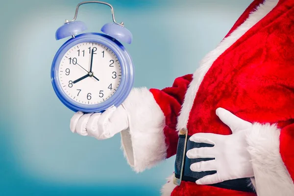 Santa Claus holding alarm clock on blue background, Christmas arrival concept