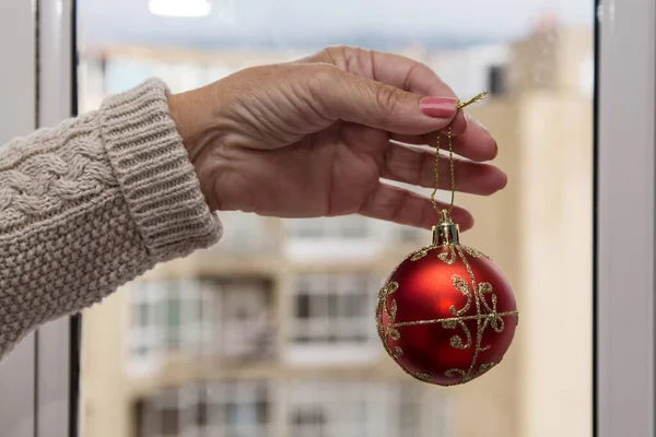 Christmas ball decor in women hand. Christmas greeting card. Woman\'s hands hold christmas or new year decorated gift.