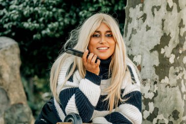 Güzel, iri yarı bir kadın parkta sesli mesaj ya da sesli mesaj yolluyor.