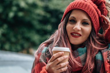 Ateşli bir kadın sokakta bir şeyler içer. 