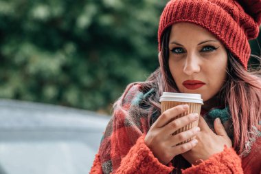 Ateşli bir kadın sokakta bir şeyler içer. 