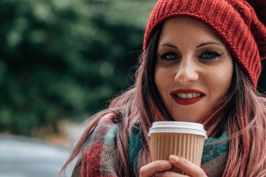 Ateşli bir kadın sokakta bir şeyler içer. 