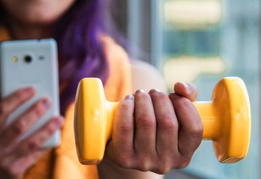 Spor salonunda telefon kullanan genç kadın