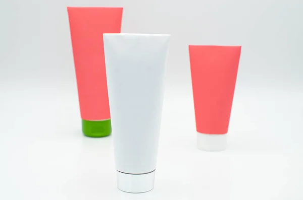 Beyaz bir arka plan üzerinde izole kırmızı ve beyaz boş kaplama ile üç farklı boyutu kozmetik veya Tıp tüpler