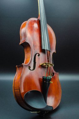 Dinamik bir pozisyonda profesyonel keman biraz karanlık bir zemin üzerine bir stüdyoda ışık aydınlatma konser benzer ateş tarafına hareket ettirildiğinde