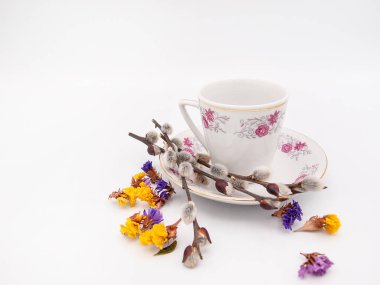 Güzel süslü porselen espresso fincan bir plaka ile birlikte birkaç söğüt twigs ve beyaz bir arka plan üzerinde izole dağınık limonium çiçek