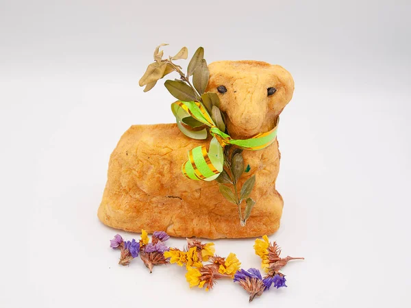 Traditional religious Easter bread baked in a form of a lamb with dried flowers and a ribbon isolated on a white background
