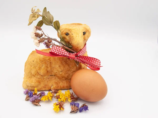 Traditional religious Easter bread baked in a form of a lamb with dried flowers, a ribbon and a chicken\'s egg isolated on a white background