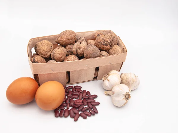 Ceviz kuru fasulye, sarımsak ve beyaz bir arka plan üzerinde sağlıklı vitamini zengin beslenme örnek olarak izole iki yumurta üç başkanları ile sepet