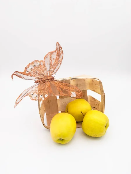 Silindir eğik sepetle sarı goldspur elma ve beyaz bir arka plan üzerinde izole bir sahte sentetik kelebek dışarı