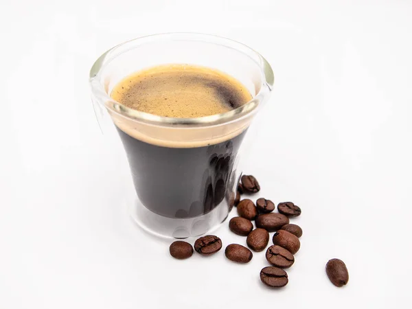 Glass of arabica espresso coffee with a few roasted coffee beans isolated on a white background