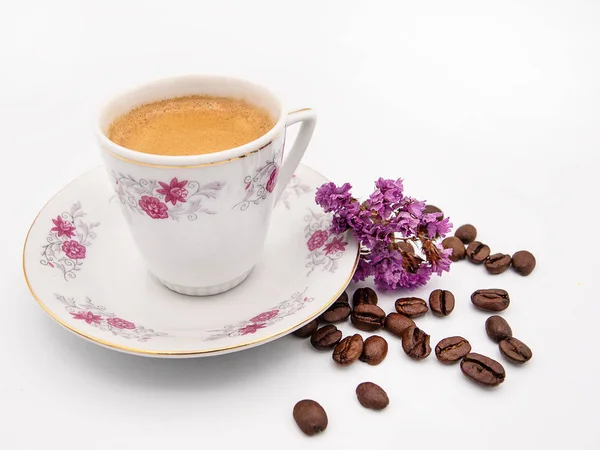 Porselen fincan arabica espresso kahve kavrulmuş kahve çekirdekleri ve limonium çiçekler beyaz bir arka plan üzerinde izole bir grup ile 