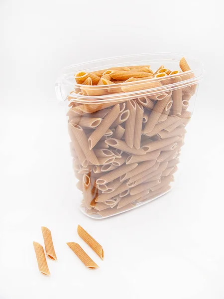 Beyaz bir arka plan üzerinde izole İtalyan penne makarna ve bol şeffaf plastik mutfak kabı