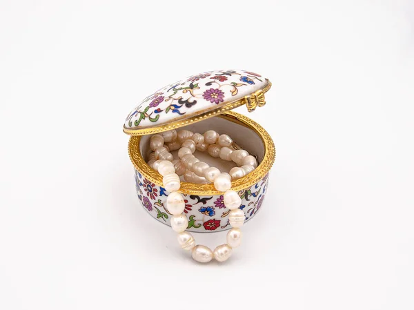 Güzel süslü porselen mücevher kutusu çiçek bir sebebi ve bir vintage yetenek içeriden gösterilen bir deniz inci kolye ile beyaz bir arka plan üzerinde izole