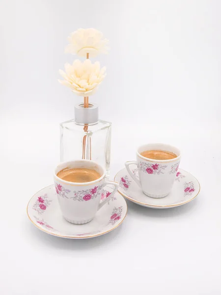 İki çiçek porselen bardak kahve espresso ve bir aranjman beyaz bir arka plan üzerinde izole iki sentetik kasımpatı çiçeği ile süslü