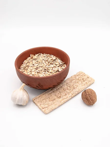 Beyaz bir arka plan üzerinde seramik tabak bir diyet gevrek ekmek veya bir sarımsak ve ceviz, sağlıklı beslenme, bir kavram olarak dekore edilmiş bisküvi ile kuru yulaf ezmesi izole