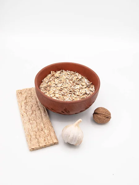 Beyaz bir arka plan üzerinde seramik tabak bir diyet gevrek ekmek veya bir sarımsak ve ceviz, sağlıklı beslenme, bir kavram olarak dekore edilmiş bisküvi ile kuru yulaf ezmesi izole