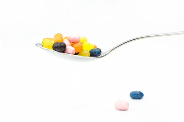 Renkli jöle fasulye ve biraz-in onları dolu gümüş çorba kaşığı dağılmış, beyaz bir arka plan üzerinde izole